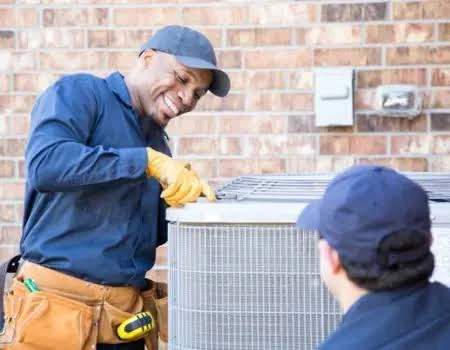 Two technicians carrying out maintenance on an outdoor air conditioning system
