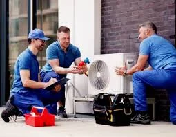 Technicians discussing a repair beside an outdoor cooling unit
